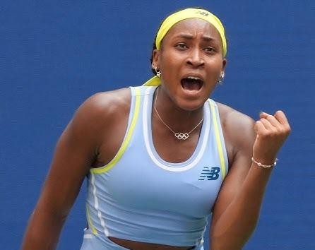 Coco Gauff uderza forhend na korcie tenisowym podczas meczu, w tle rozmazany stadion.