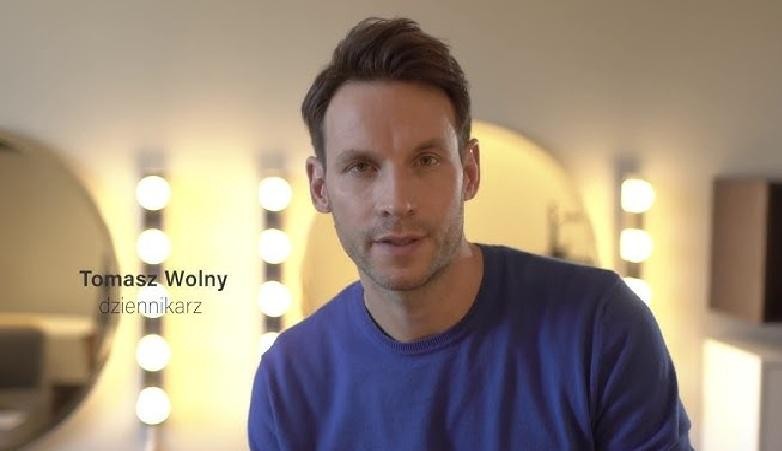 Tomasz Wolny, wykładowca, w tle regał z książkami lub uniwersytecka aula, symbolizujący jego wykształcenie i rolę akademicką.