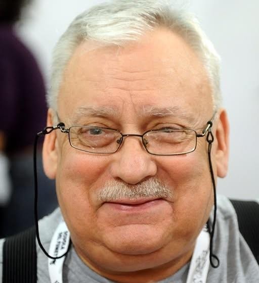 Jesienny widok na Skwer Geralta z Rivii w Łodzi, z kolorowymi drzewami i tabliczką z nazwą skweru.