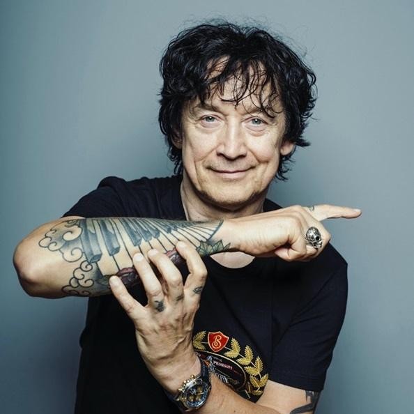 Jan Borysewicz w zbliżeniu, z pasją grający na gitarze elektrycznej podczas koncertu, z intensywnym oświetleniem scenicznym.