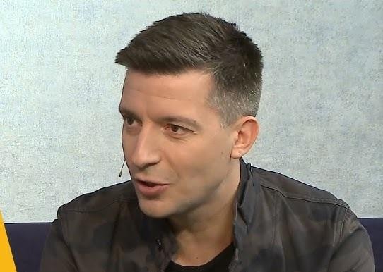 Michał Cessanis w podróży, w egzotycznym miejscu, z uśmiechem na twarzy, oddający radość z odkrywania świata.