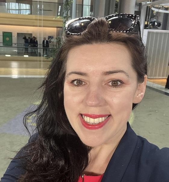 Dominika Ćosić przemawiająca na konferencji w Brukseli, w tle budynek instytucji europejskiej.