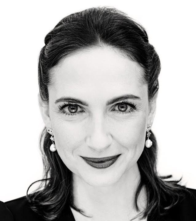 Aktorka Anna Cieślak w dramatycznej roli na scenie teatralnej, oświetlona pojedynczym reflektorem, z intensywnym wyrazem twarzy.