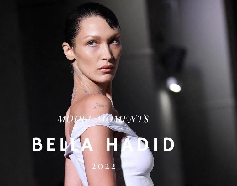 Bella Hadid uśmiechnięta, w interakcji z fanami lub podczas wydarzenia charytatywnego, ukazująca jej zaangażowanie społeczne.
