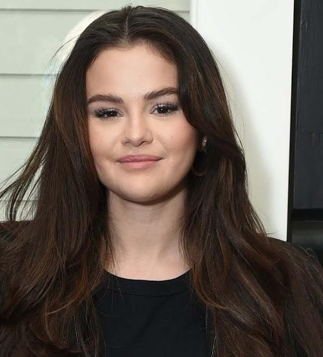 Selena Gomez występuje na scenie podczas koncertu, trzymając mikrofon.